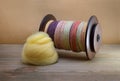 Spinning wheel bobbin filled with hand spun yarn made of sheepÃ¢â¬â¢s wool with a pile of yellow merino roving Royalty Free Stock Photo